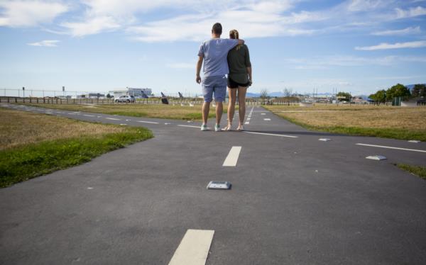 A couple at flight path park watching planes land.