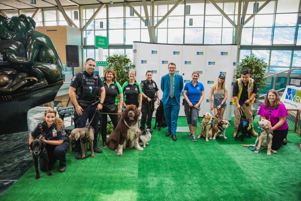 YVR celebrated the first ever Dog Days of Summer event at the airport. From left to right are representatives from Canada Border Services Agency (CBSA); Transit Police; St. John Ambulance; Securiguard; Reg Krake, Director, Customer Care, Vancouver Airport Authority; BC & Alberta Guide Dogs; Mister Bentley; YVR’s Wildlife Team in partnership with Avisure and Pacific Assistance Dogs Society (PADS).
