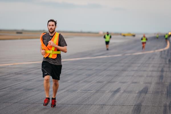 A man in a high-visibility vest runs down the North Runway at YVR during the Terry Fox run.