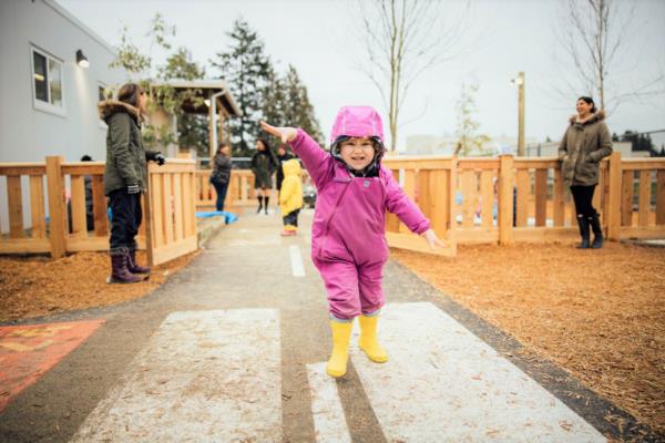 Child with arms spread wide like a plane entering the new Little Wings play area