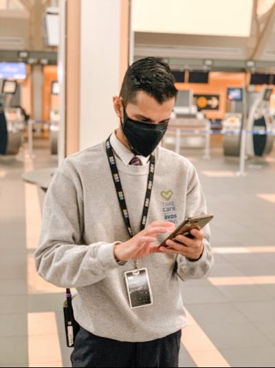  Jat portant un pull gris dans le terminal regardant son téléphone portable.
