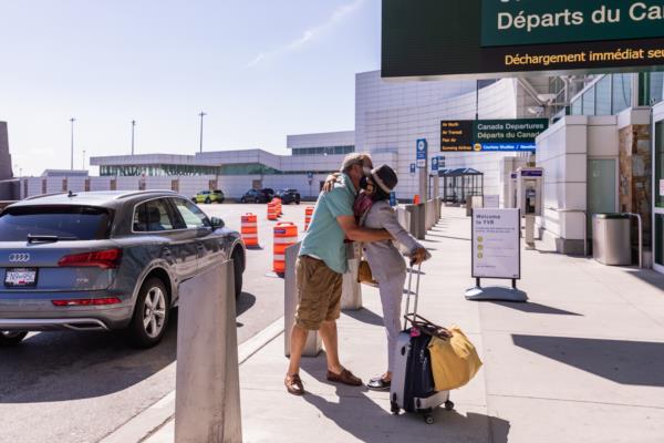 Une voyageuse étreignant un ami ou un parent à l'extérieur sur le trottoir des départs intérieurs.