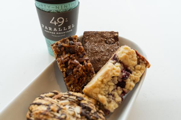 Plate of pastries with a cup of coffee from 49th Parallel behind