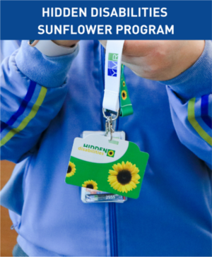 The text at the top of the image says Hidden Sunflower Disabilities Program. The image shows a close-up of a person in a blue jacket is holding a green lanyard with a green card with yellow sunflowers on it and words that say Hidden Disabilities.