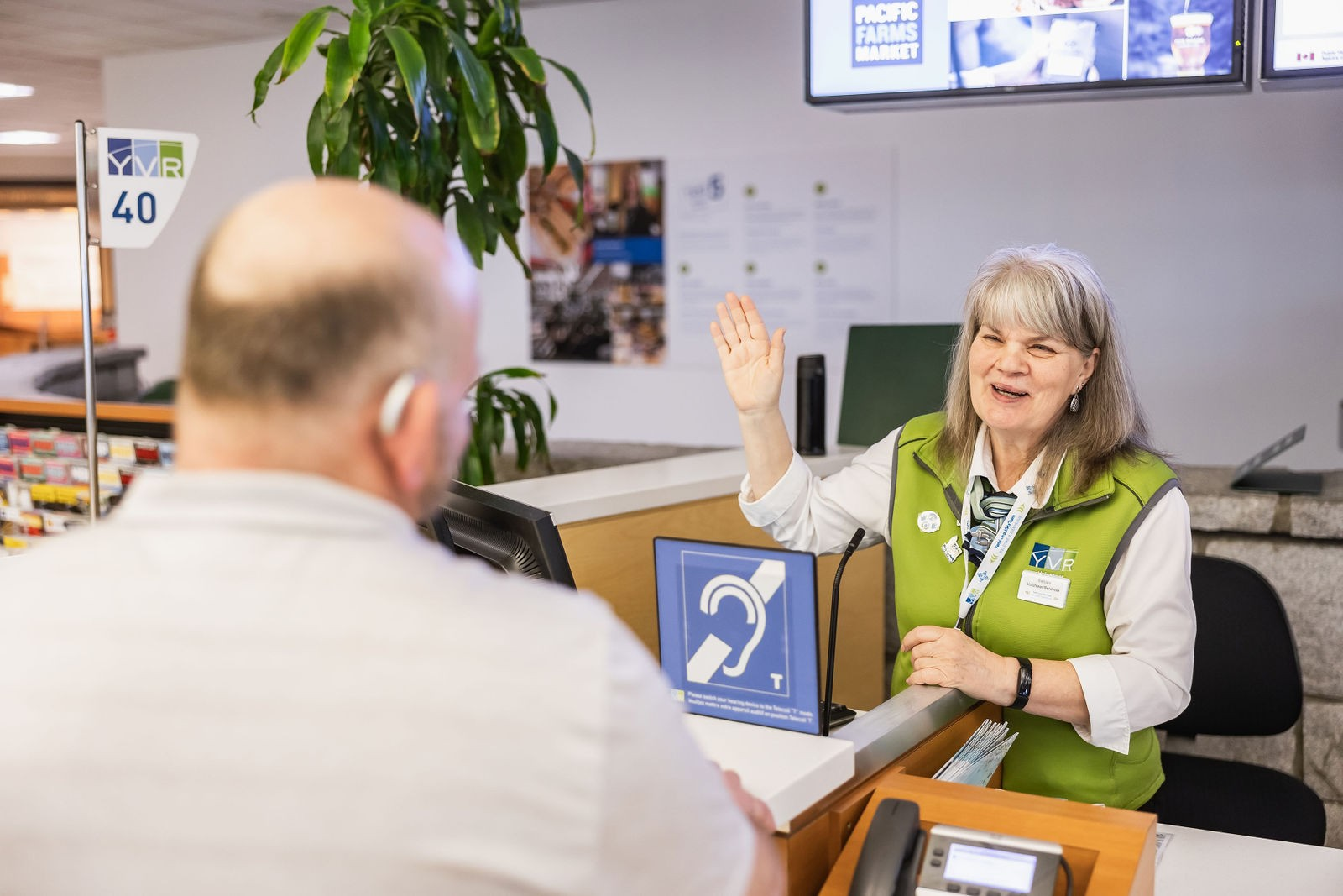 Green coat volunteer talking to customer at the airport